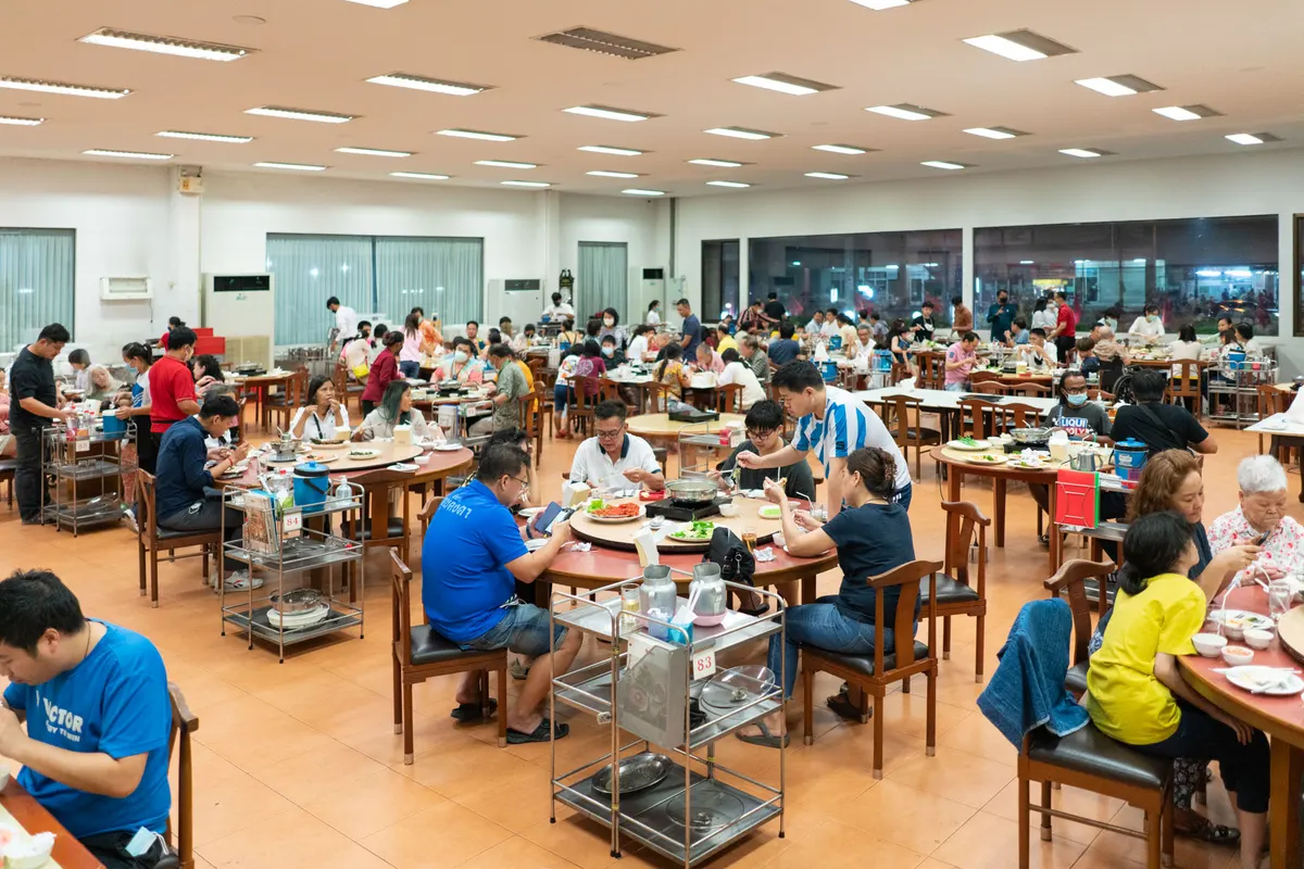 ภาพบรรยากาศความคึกคักภายในห้องอาหารขนาดใหญ่ของเรือนเพชรสุกี้ สาขาศรีนครินทร์ ลูกค้าแบบครอบครัวและกลุ่มเพื่อนจำนวนมากกำลังนั่งรับประทานสุกี้ร่วมกันที่โต๊ะกลมอย่างอบอุ่น สะท้อนถึงความเป็นร้านอาหารยอดนิยม